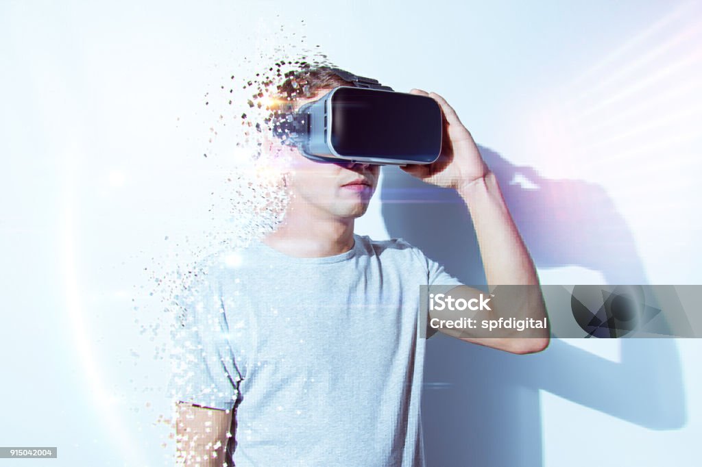 Young man wearing virtual reality goggles in modern coworking studio. Smartphone using with VR headset. Horizontal Virtual Reality Stock Photo