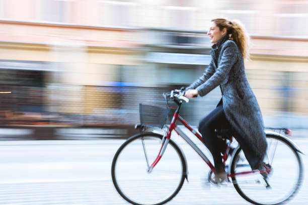 frau fährt fahrrad in der stadt - frau fährt fahrrad stock-fotos und bilder