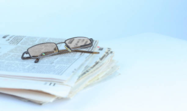 istock stack of Newspapers and glasses isolated on white 915044918