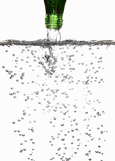 Sparking drink being poured into a glass Sparkling Water Pouring Into a Glass on white background pouring water from bottle stock pictures, royalty-free photos & images