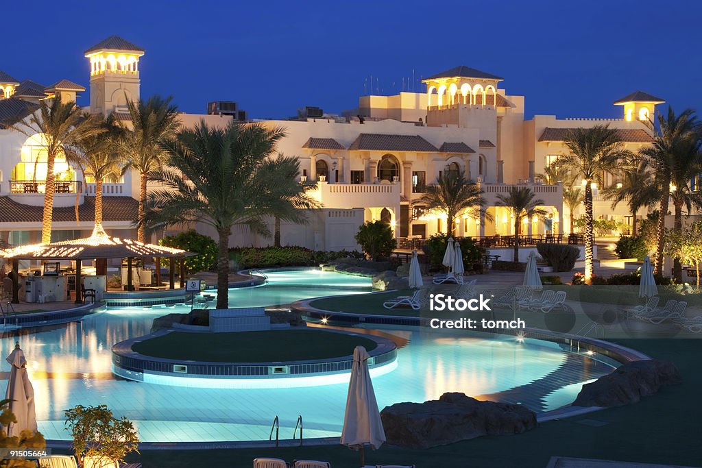 Beautiful Resort Pool on evening. Tourist resort with pool, hotels, restaurants, spa, playground in Egypt. Taken at dusk with a tripod to align the artificial light and the brightness of the evening blue sky. Egypt Stock Photo