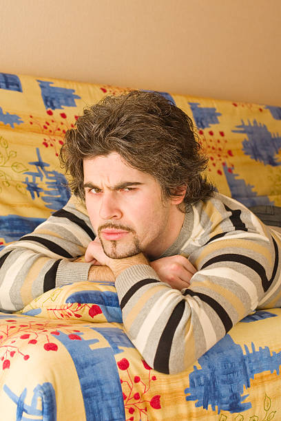 istock Young frowning handsome male on colourful sofa 91505769