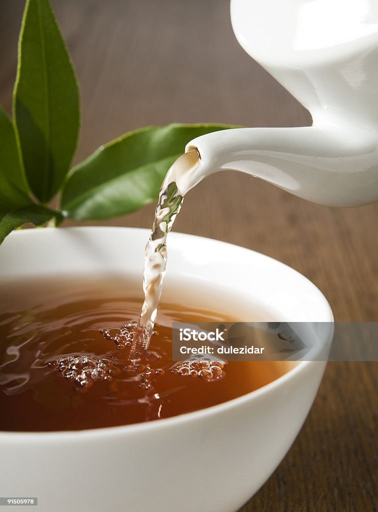 Tea being poured into a teacup out of a kettle Cup of green tea pouring close up shoot Breakfast Stock Photo