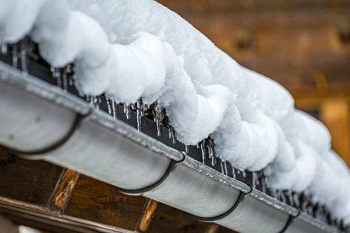 Snow on a wooden roof thawing in small ice cones