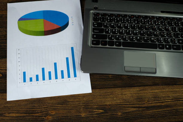 istock Notebook laptop computer and financial graph on white paper on working table, business planning vision and finance analysis concept. 915071620
