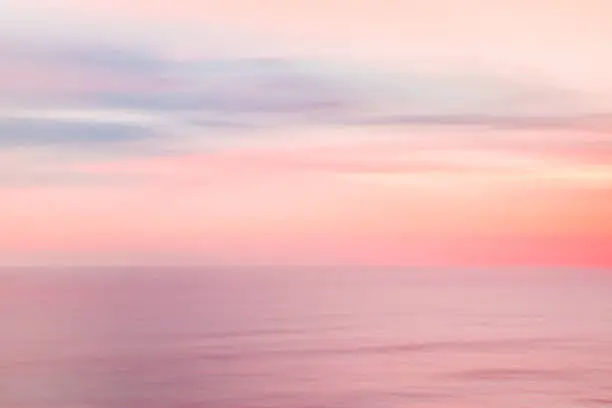 Defocused sunrise sky and ocean nature background with blurred panning motion.