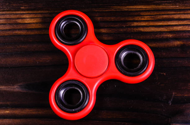 istock Red fidget spinner on wooden desk. Top view 915083026