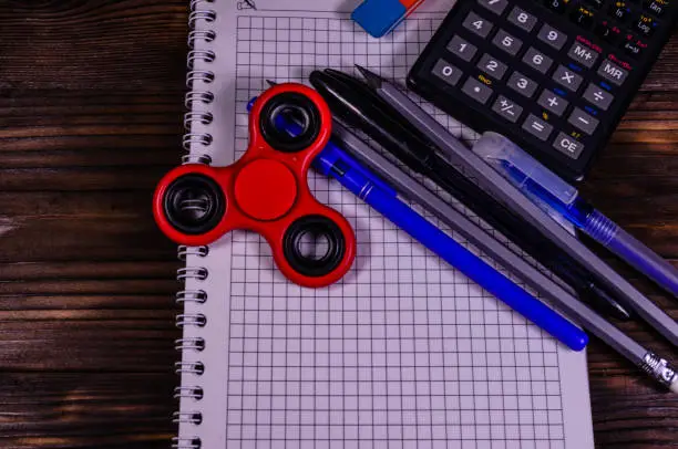 Photo of Spinner and different stationeries on wooden desk. Top view