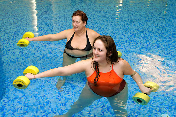 Two fat  women in water on training stock photo