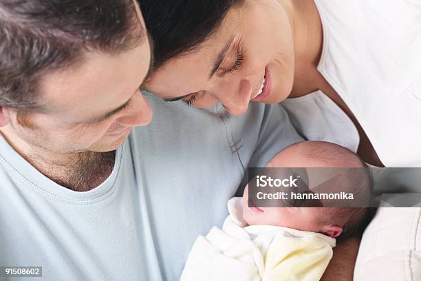 Happy Parents Holding And Looking Down At Their Newborn Baby Stock Photo - Download Image Now