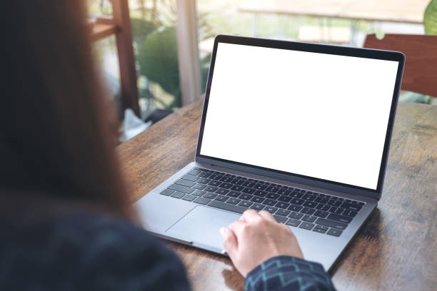 istock Mockup image of a hand using and touching laptop with blank white desktop screen on wooden table in cafe 915087094