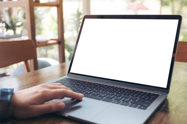 istock Mockup image of a hand using and touching laptop with blank white desktop screen on wooden table in cafe 915087110