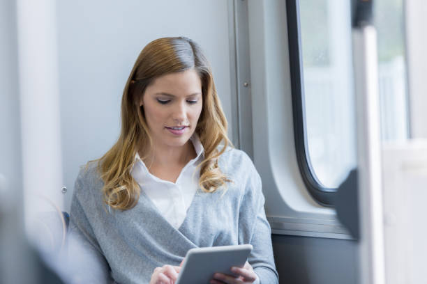 istock Woman works on digital tablet while riding commuter train 915093382