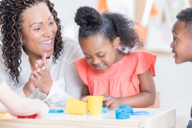 istock Little girl with Down Syndrome playing with modeling clay 915093572