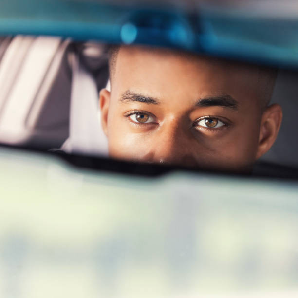 junger mann sieht im rückspiegel während der fahrt - rear view mirror car mirror rear view stock-fotos und bilder
