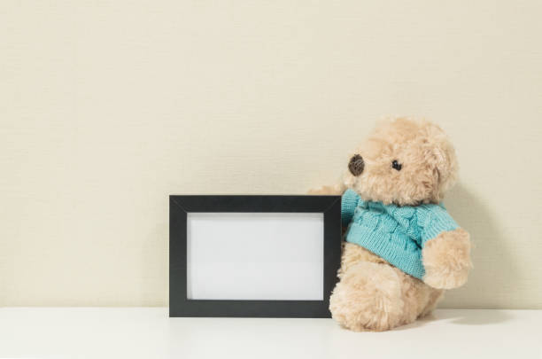 istock Frame for a photo with brown bear doll on wall room background 915094532