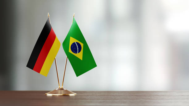 istock Brazilian And German Flag Pair On A Desk Over Defocused Background 915094744