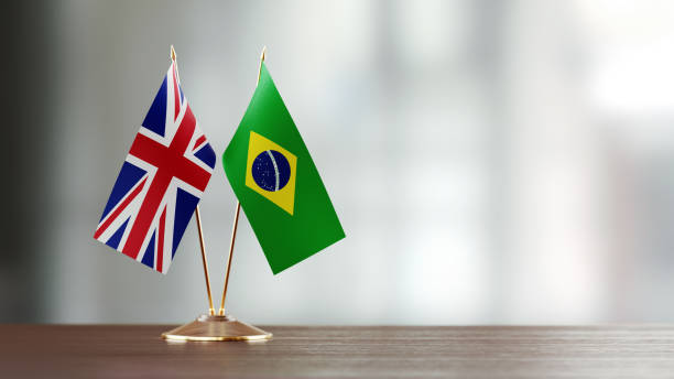 istock Brazilian And British Flag Pair On A Desk Over Defocused Background 915095218