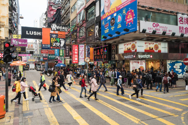 menschen überqueren einer viel befahrenen straße in der sehr belebten mong kok einkaufsviertel in kowloon, hongkong - hong kong billboard asia china stock-fotos und bilder