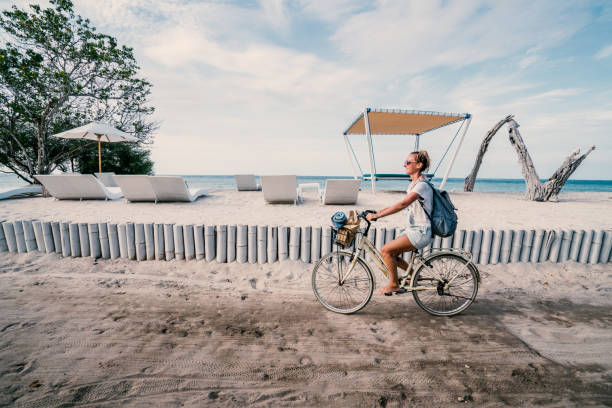 Girl riding bicycle by the beach in the morning, Indonesia Cheerful young woman on vacations cycling by the beach in the morning, people travel holidays concept. gili trawangan stock pictures, royalty-free photos & images