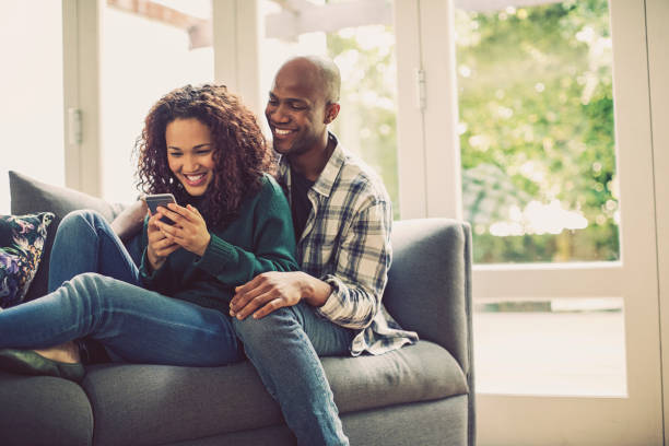 istock Happy couple using smart phone on sofa at home 915112978