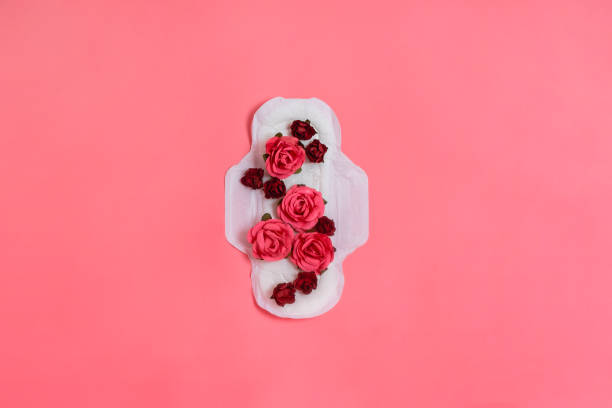 cojín sanitario blanco con flores rojas y rosadas, concepto positivo de salud o cuerpo de mujer. fondo rosa.  flatlay. copyspace - menstruación fotografías e imágenes de stock