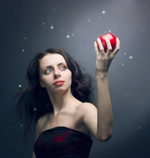 Young woman with red apple on top of head