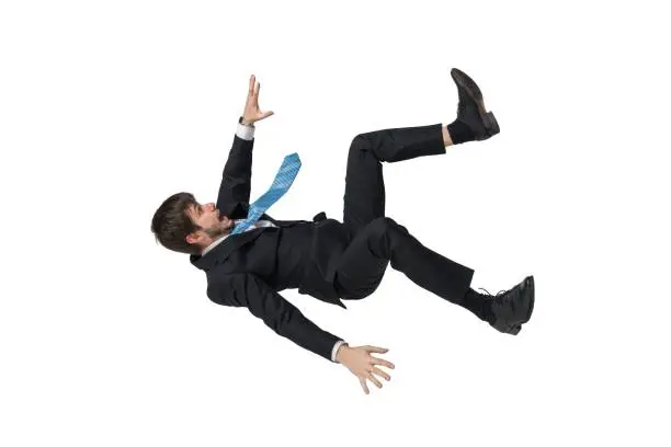 Photo of Young businessman falling down in free fall. Isolated on white background.