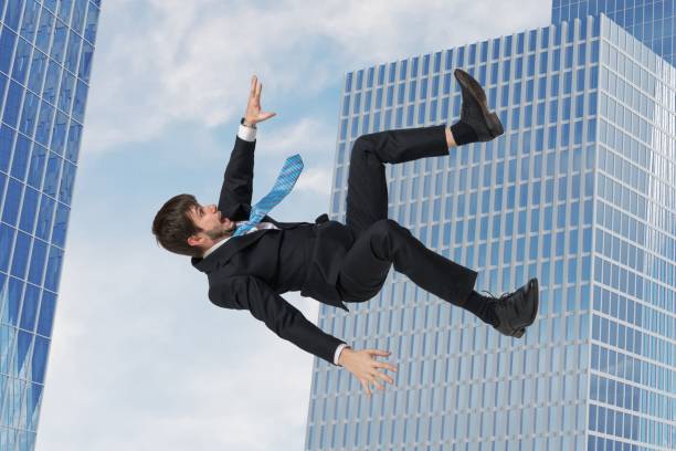 istock Young businessman falling down in free fall. Skyscrapers in background. 915116452