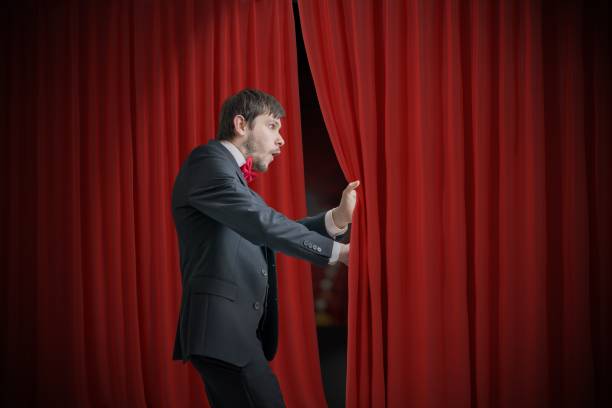 acteur curieux ou illusionniste est regarder derrière le rideau rouge et est surpris. - hiding fear men peeking photos et images de collection