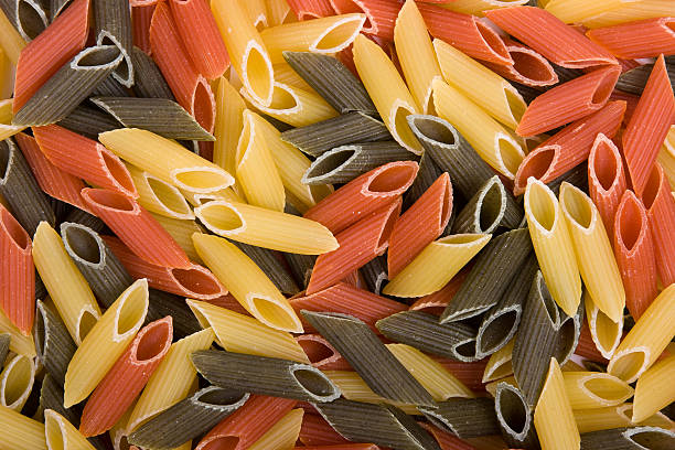 Colored raw penne as background. stock photo