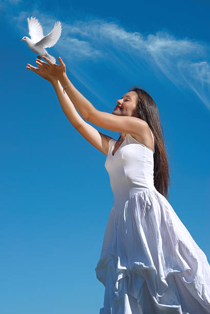 The happy woman releasing a pigeon in sky stock photo