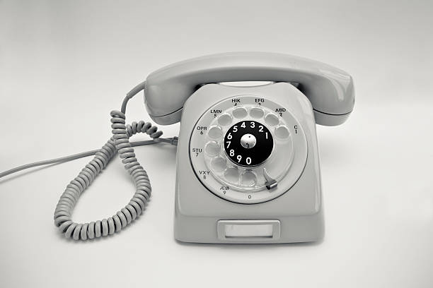 Grey retro phone on a dark wood desk. It was used in Spain around 1960\\'s-1970\\'s. It has space for some text.