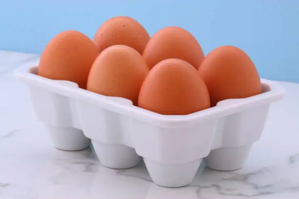 Healthy free range eggs on porcelain crate over vintage carrara marble kitchen station.