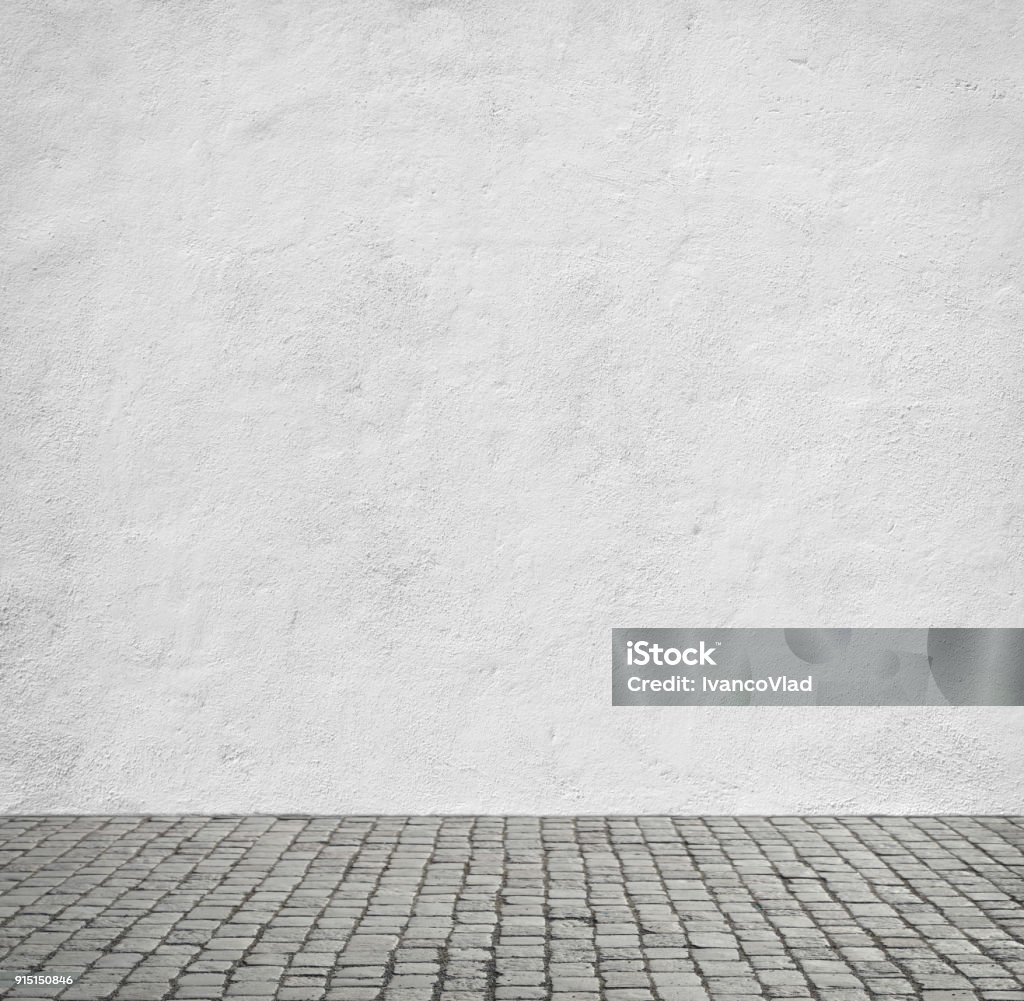 White wall of the house Old white wall and cobblestone floor. Flooring Stock Photo