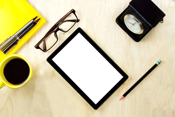 istock Tablet PC with blank white screen display and eyeglasses, cup of coffee and office supply on the wooden working table for business and education concepts. 915157236