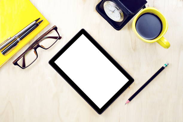 istock Tablet PC with blank white screen display and eyeglasses, cup of coffee and office supply on the wooden working table for business and education concepts. 915157278