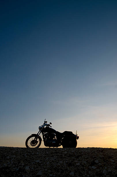 A silhouette of a classic motorcycle against a sunset