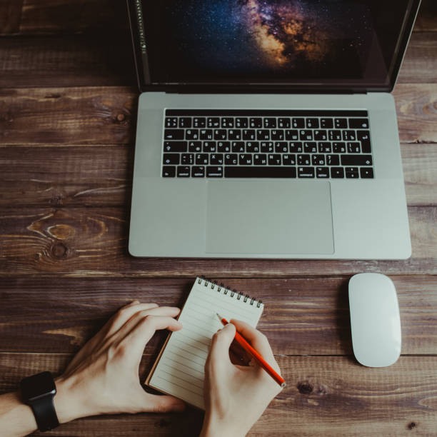 istock Man is writing on draft notepad and using laptop computer at home office. Freelance lifestyle workplace 915160240
