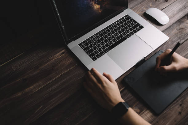istock Man designer is working using laptop computer and graphics tablet at home office. Professional occupation workplace 915160444