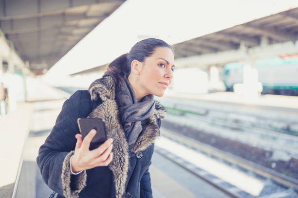 istock Young woman using a phone at a railroad station 915161194