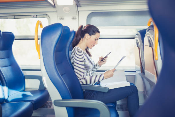 istock Young woman traveling by train, using mobile phone and browsing paper documents 915161258