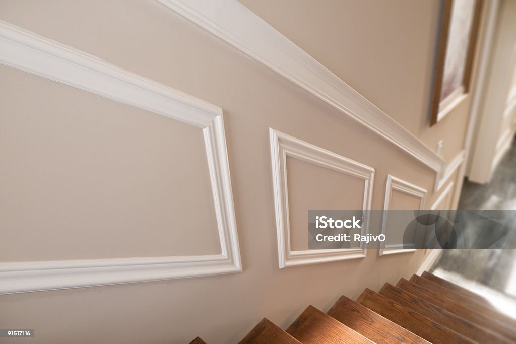 Stair view of interior of a new house The interior of a house, with focus on decorative molding on the wall along a wooden staircase. Granite floors can be seen below the stairs. Drywall Stock Photo