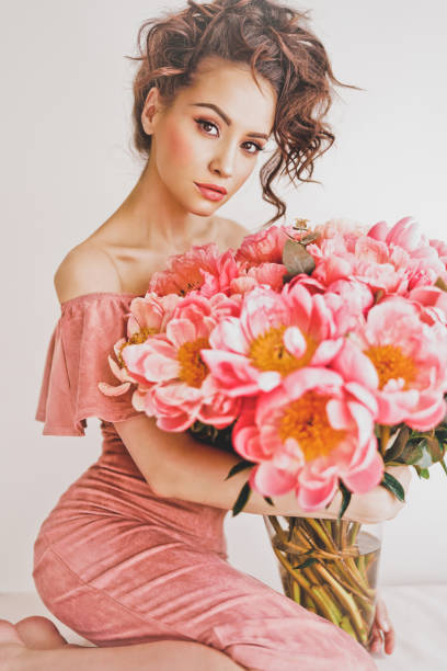молодая женщина в розовом платье с розовыми пионами - day expressing positivity clothing desire стоковые фото и изображения