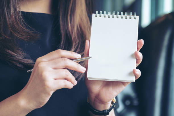istock woman holding and showing a blank notebook 915182752