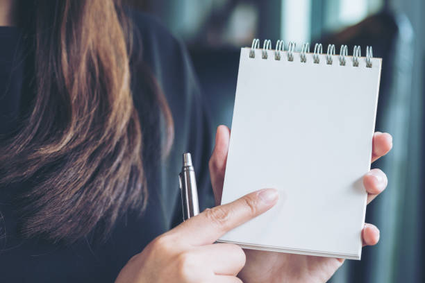 woman holding and showing a blank notebook in office