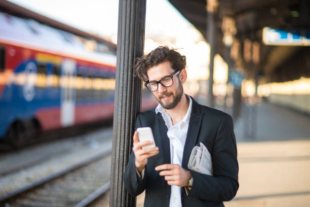 istock Businessman using mobile phone at train station 915186368