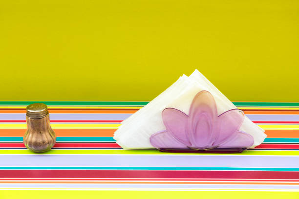 Pepper shaker and napkins on a striped tablecloth in 60s retro style