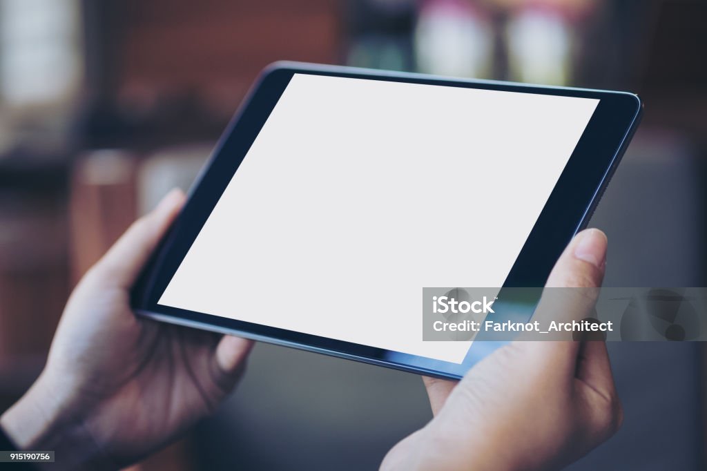 Imagen de la maqueta de la mano de la mujer negra tablet pc con pantalla en blanco en blanco en madera café - Foto de stock de Tableta digital libre de derechos