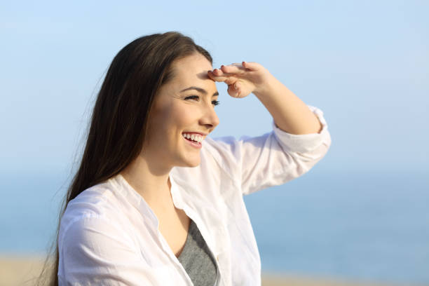 istock Woman scouting with hand on forehead on the beach 915197370